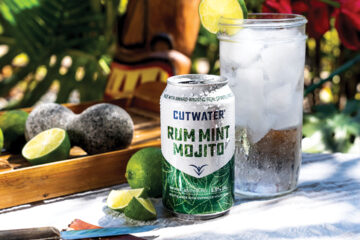 Rum Mint Mojito CutWater Spirits can posed with an ice cold drink, limes, and a garden tiki backdrop