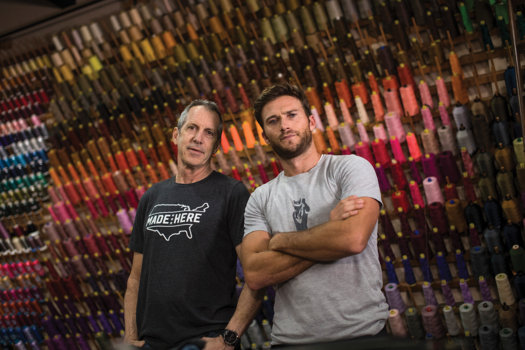 Dane Chapin and Scott Eastwood in front of a wall of colorful spools of string