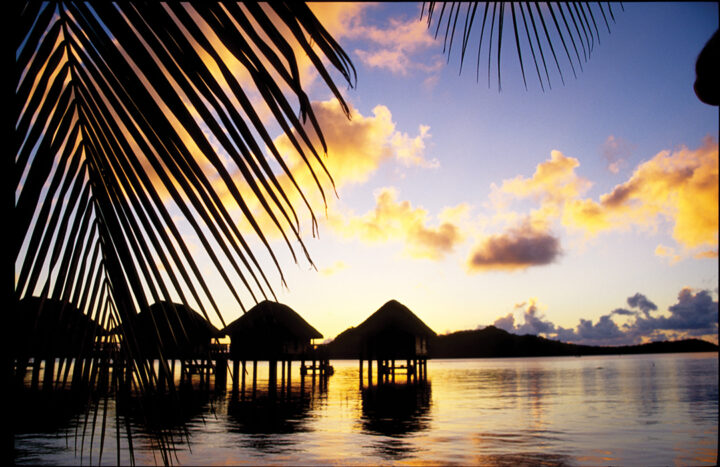 Silhouettes of overwater bungalows in Huahine, French Polynesia