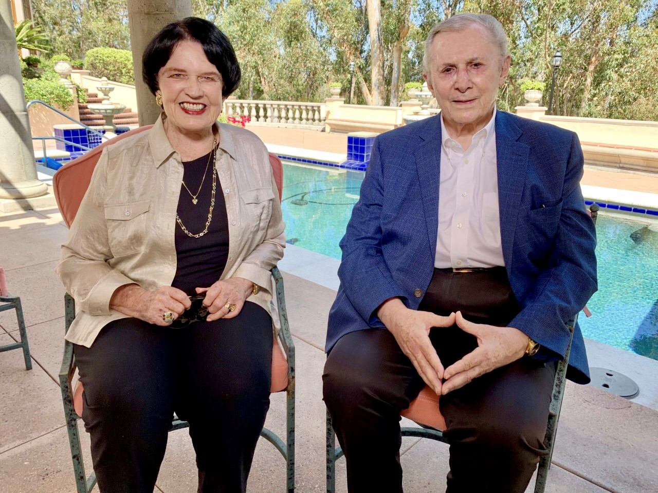 Debbie and Warner Lusardi sitting outside in front of their pool