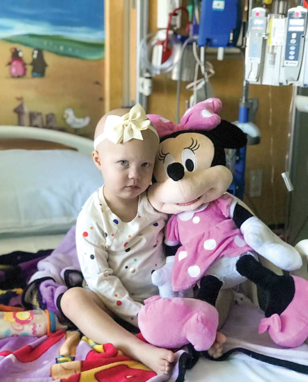 Sick child in hospital bed holding Minnie Mouse stuffed animal