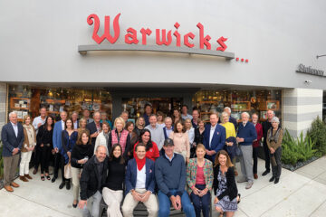 Nancy Warwick (front row, second from left), Steve Avoyer (with red scarf), and Jack McGrory (front, center), along with the group of investors who purchased the Girard Avenue building in which Warwick’s is located