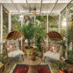 A screened-in porch decorated with potted plants is a relaxing setting for reading and relaxing
