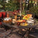 The Moxhams love to entertain outside on their courtyard where the spread includes spiced iced tea, fruit, cookies, and chocolates. Neighbor Robert A. Clark helped them landscape the space with pots of plants and flowers
