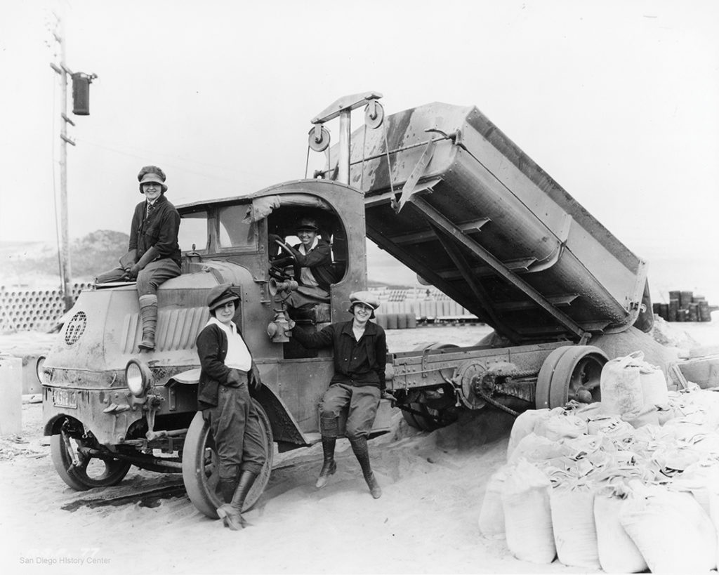 Black and white photo of Lilian Rice in the driver’s seat during Rancho Santa Fe construction, along with Mrs. Norman McLean (on hood), Virginia Smith (standing), and Bertha Kreuziger