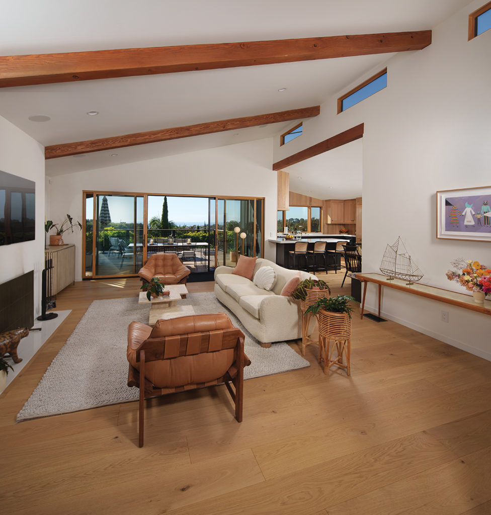 The living room in the modern ranch-style home, inspired by the work of the late designer/builder Cliff May, has a high, pitched ceiling and clean-lined furnishings, and opens onto a terrace through sliding glass doors to bring the outdoors in