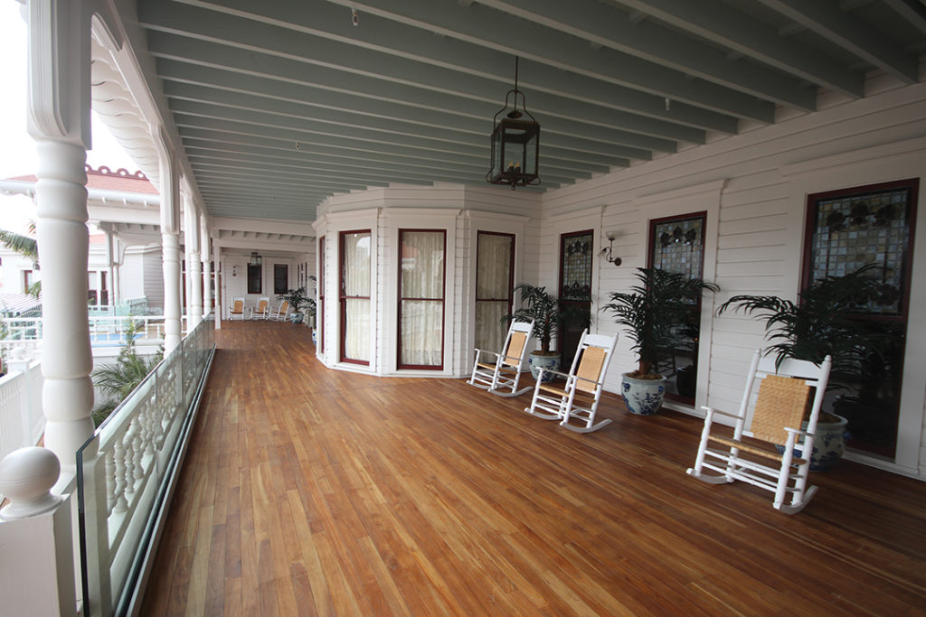 The restored veranda with added glass guardrails, teak floor, and Victorian details
