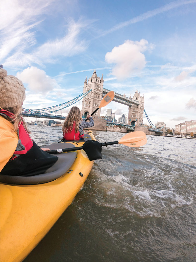 Two women kayaking on River Thames, Tower Bridge, London, England