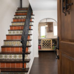 The staircase, once carpeted and with floral wallpaper, was redesigned with wrought iron railings and Mexican tile