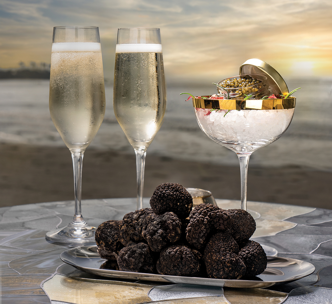 Lounge at The Marine Room’s Champagne and caviar with truffles with view of the pacific ocean at sunset behind it