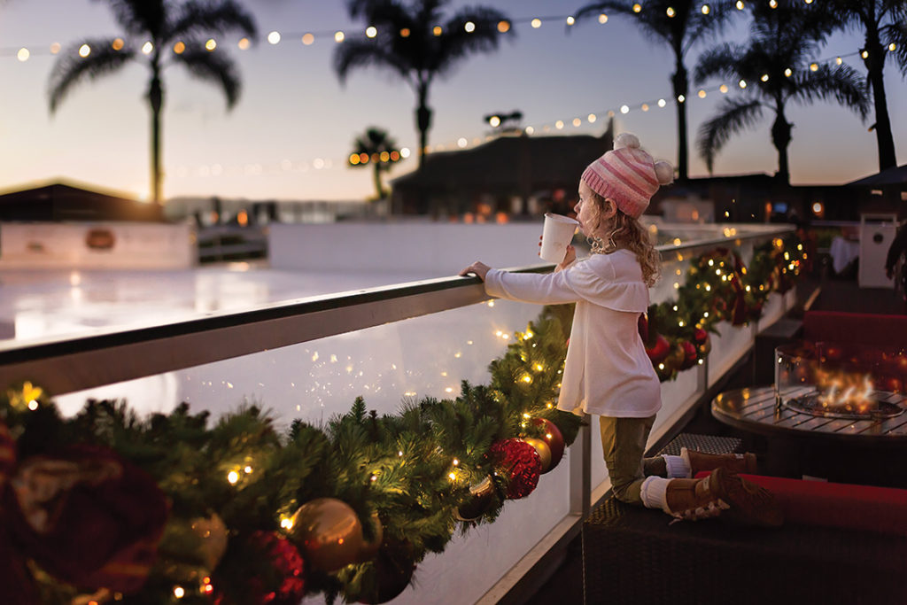 Little girl sipping hot chocolate in front of the ice rink at the Hotel Del Coronado at twilight in San Diego, CA