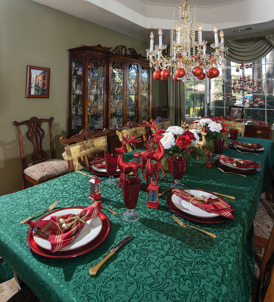 The elegant dining room, set for a Christmas feast, is decked out in a holiday palette of red, green, and gold