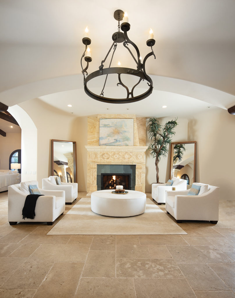 The foyer, centered with a stone fireplace, includes a chic, comfortable seating area. Flooring throughout the house is crafted of tumbled limestone from France