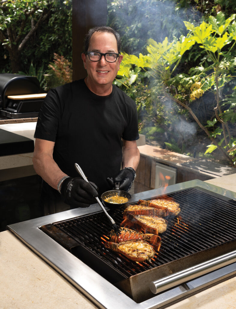 Sam Zien, best known as “Sam the Cooking Guy,” grills up lobster tails with garlic-ginger butter on his backyard barbecue