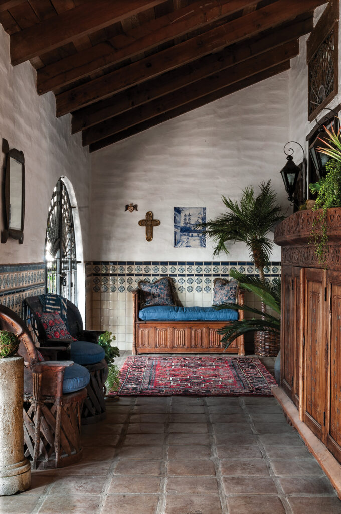 The entrance patio, Parisi’s favorite room, offers a mix of antique Mexican equipale chairs, a carved bench from Spain, and an antique cabinet from Brazil