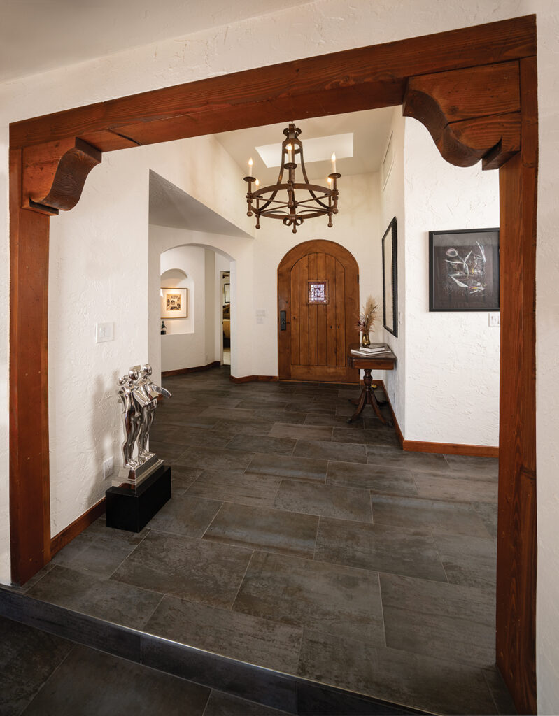 White plaster walls with niches for the couple’s art collection contrast with a rustic Mexican-inspired door. The flooring is porcelain tile
