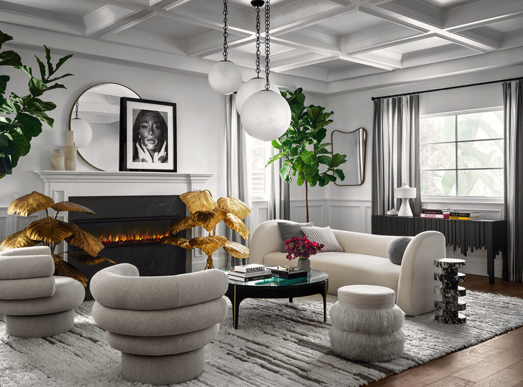 Model Winnie Harlow’s fireplace is flanked by Tommaso Barbi brass leaf lamps, a magnifying lens coffee table designed by LA’s ma+39, and a shaggy wool rug by Woven. A fan created the photorealistic drawing of Harlow over the mantel