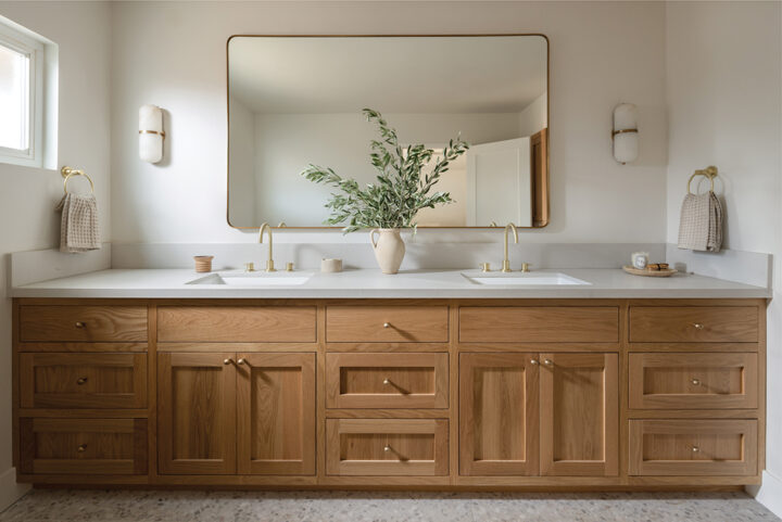 In the master bath, Valletta replaced dated white painted cabinets with white oak, added durable Caesarstone countertops in “fresh concrete,” used Moroccan Zellige in the showers, and tiled the floors in terrazzo. Alabaster wall sconces and a large mirror complete a look that is simple and elegant
