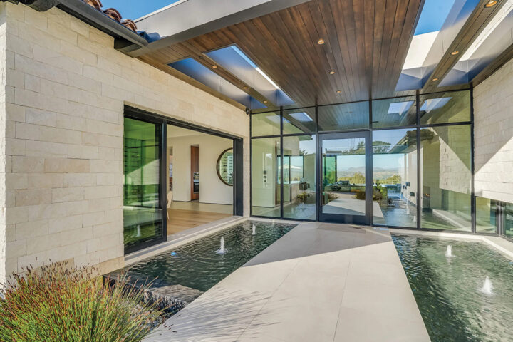 The pivot entry door leads to breathtaking views through the walls of glass that overlook the zero-edge radius pool