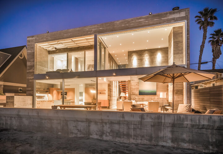 The home, just steps from the sand, all aglow at night, has 50 feet of ocean frontage