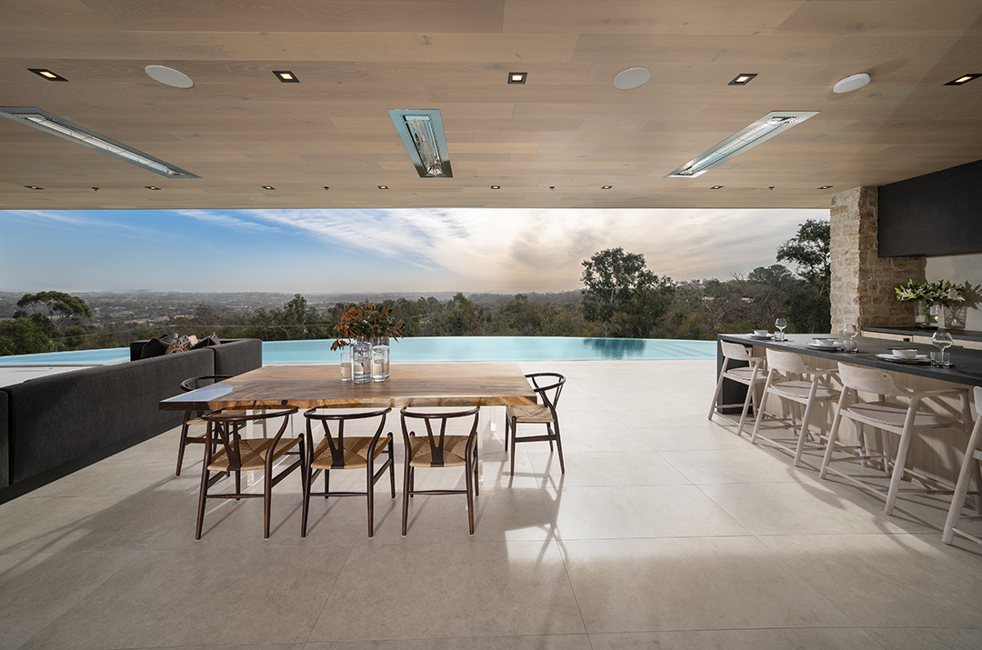 The patio overlooking the 80-foot infinity pool has spaces for lounging, dining, and cooking in the outdoor kitchen