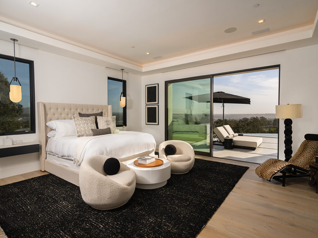 The master bedroom opens onto a private patio with lounges by the fireplace. Hardwood floors in white oak are from Christine Baker at Sterling Interiors with handmade, one-of-a-kind light fixtures from Allied Maker. Custom window treatments throughout the home are by Joe Blythe Installations