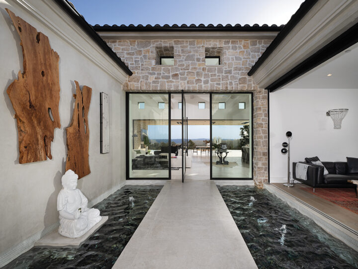 The dramatic entryway flanked by water features leads to the open living room and kitchen