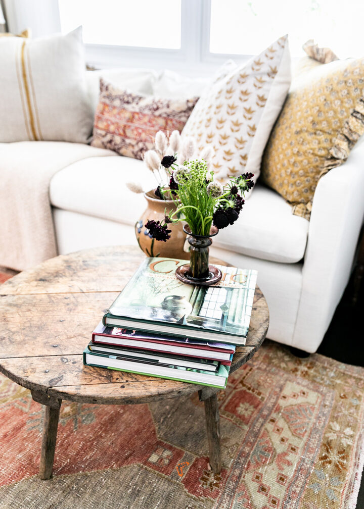 The office features a sofa bed from West Elm, pillows from The Shop Granite Bay, a coffee table from Juxtaposition Home, a desk lamp by Schoolhouse, and a purple lamp from Magnolia Mews with a custom lampshade by Lamp Shades Unlimited