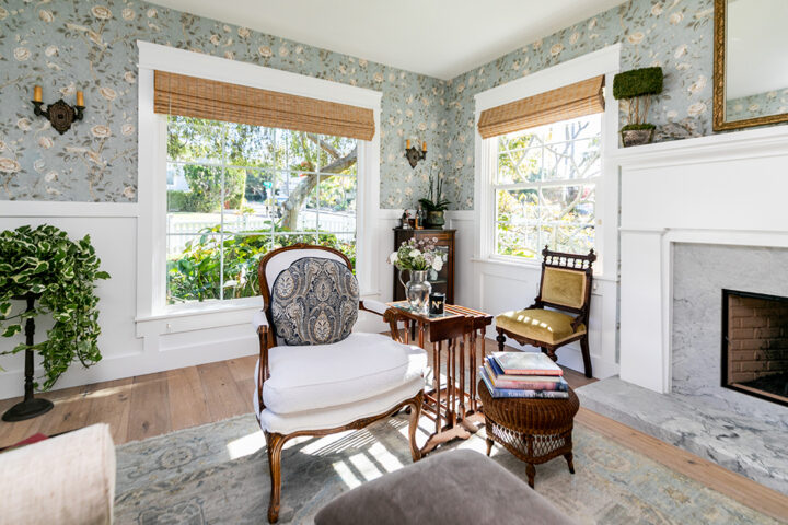 For a cottage renovation on Waverly, Mariucci tapped the spirit of the English seaside for her expat client. Here, a sweet sitting room is made more dramatic by the reclaimed mirrored barn doors that open onto it. Wallpaper is by Schumacher; antique chairs are given new life with fabric by Kravet and Perennials. Both ottomans, nesting tables, and accessories are from Girard Avenue Marketplace