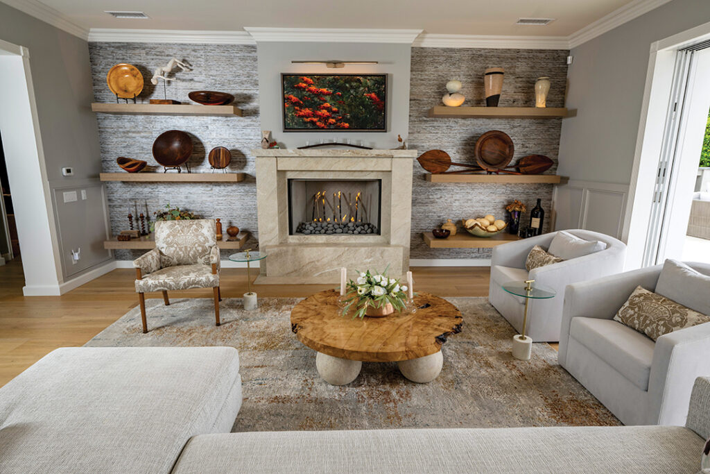 In the living room, Ron designed the fireplace and the maple burl coffee table. The bookcases hold wood accessories found on the couple’s travels, as well as gifts from friends. Artwork over the mantel is by Lyn Hiner