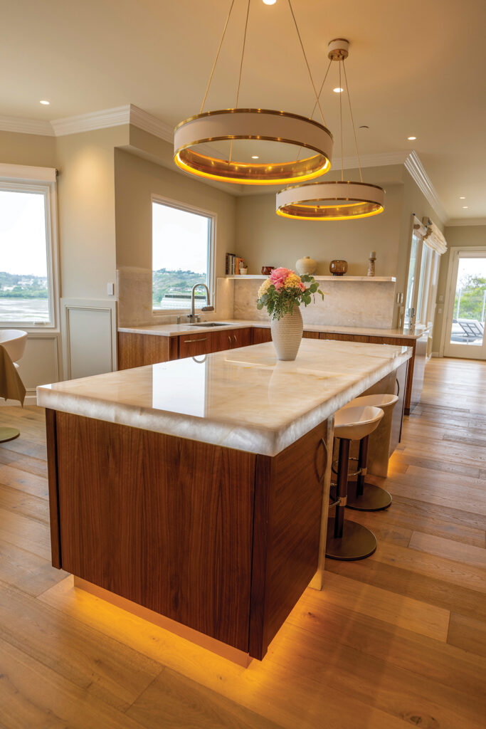 The kitchen features walnut cabinetry designed by Ron. The island is topped with Cristallo quartzite lit from below. Light fixtures are from Light Gallery Plus in Encinitas