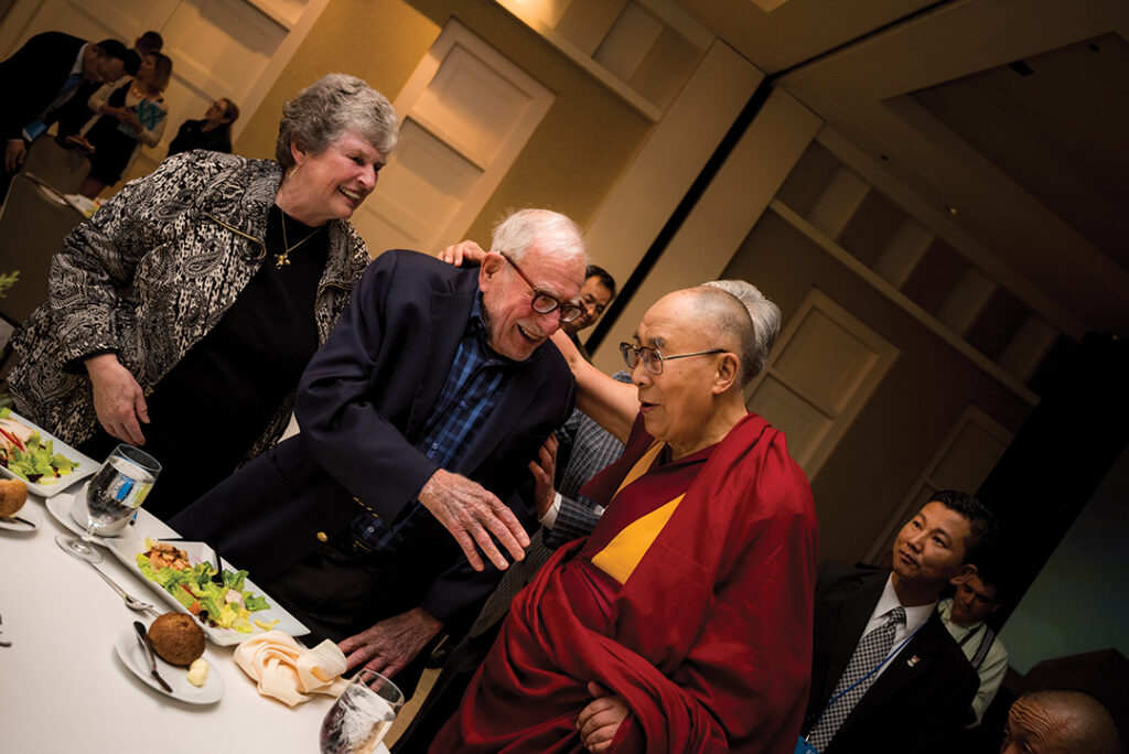 The Dalai Lama embraces Walter Munk as Mary Munk looks on