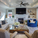 The living room is designed in a neutral palette with pops of blue and accessories that reflect the coastal setting. Family photos of the couple and their three sons adorn one wall