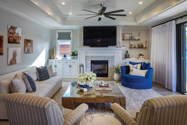 The living room is designed in a neutral palette with pops of blue and accessories that reflect the coastal setting. Family photos of the couple and their three sons adorn one wall