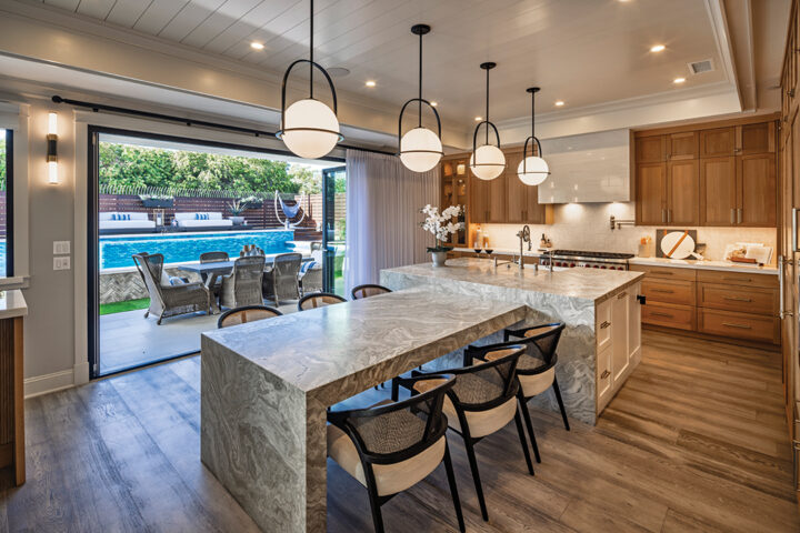 The kitchen, which opens onto the patio, features white oak cabinetry, marble counters, a quartzite dining area, and bar