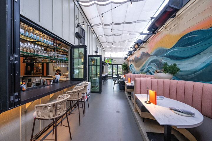 Mia’s beachy vibes extend into an alley lined with coral banquettes care of a wall-length mural of a wave in motion beneath a citrus-hued sunset from local artist Carolina Arrieta