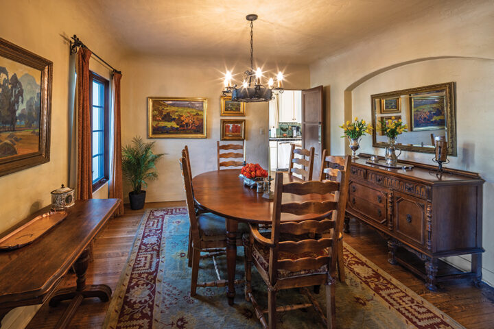 The dining room features vintage furniture, curtain finials, and a chandelier salvaged from the couple’s families. It also displays the couple’s prized collection of plein art