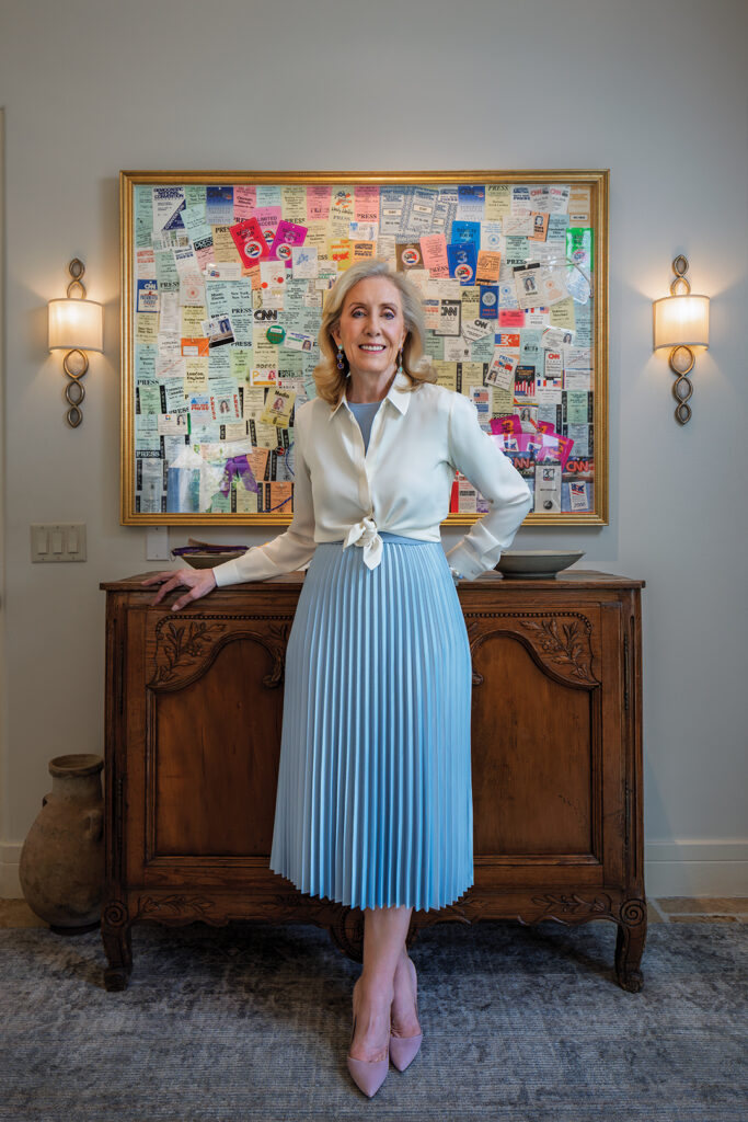 Wendy Walker poses in front of a montage of press passes from her years as a White House producer for CNN