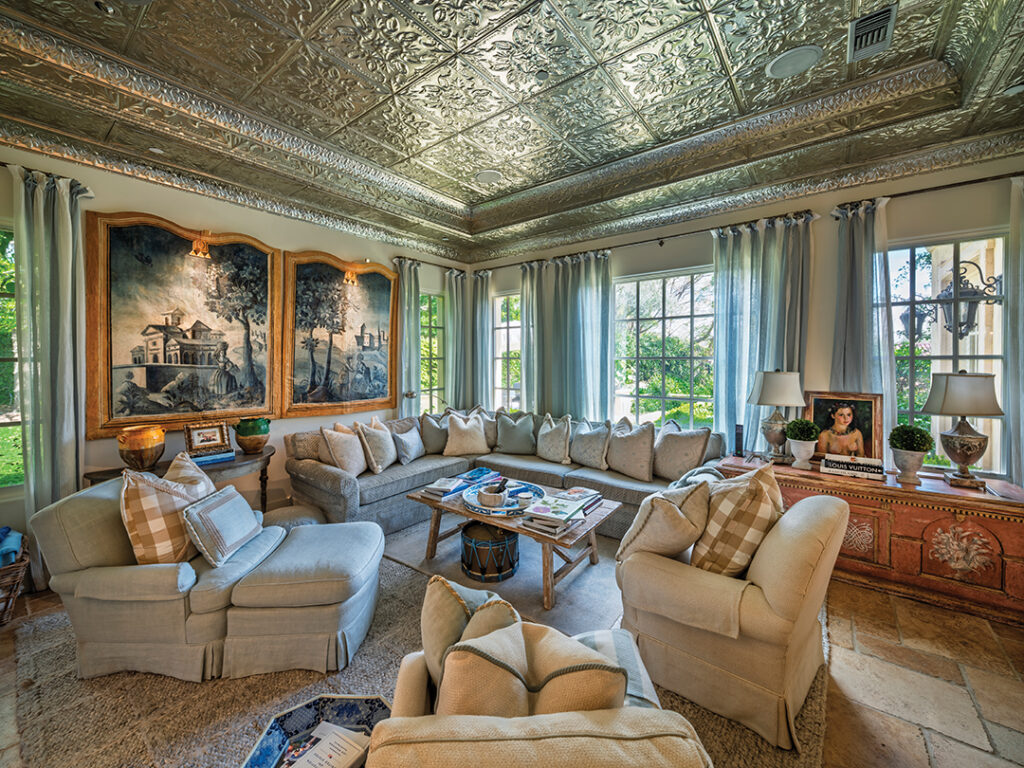 The French-inspired family room has the original tin ceiling which reminds Walker of a Paris cafe. Painted canvases over the sofa were once backdrops in a theatre