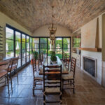 The home’s dining-reading room opens onto a patio with a firepit. The ceiling, centered with an antique chandelier, is set with old bricks from France
