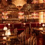 Fallen Empire, a hidden oyster and champagne bar, is tucked discreetly behind the lobby. The reservation-only jewel box bar features mirrored walls, red mohair upholstered booths with built-in champagne buckets, and an ornate mosaic floor depicting under-the-sea scenery. The double-duty bar — both cocktails and raw seafood — is heaped with decadent displays of Kumamoto oysters, scallop crudo, and uni tartare. The Champagne menu is an effervescent homage, featuring leaning rare vintages and cocktails