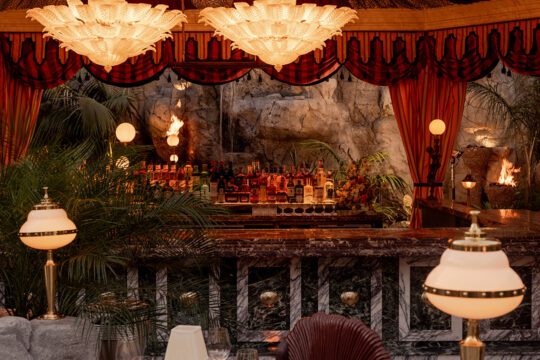 It’s the blue lagoon reimagined as Night Hawk, an open-fire Greek restaurant. Rock-formed booths and banquettes create nooks from which to review the overwrought design