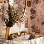 The house reveals itself through moments of personality rather than spectacle. In Garrison’s playbook, bathrooms are the main event. A powder room wrapped in custom New Orleans toile wallpaper is a personal nod to the homeowner’s time there
