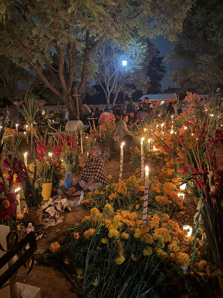 A sweet grandma sits quietly among the gravestones within this elaborately decorated cemetery in Oaxaca