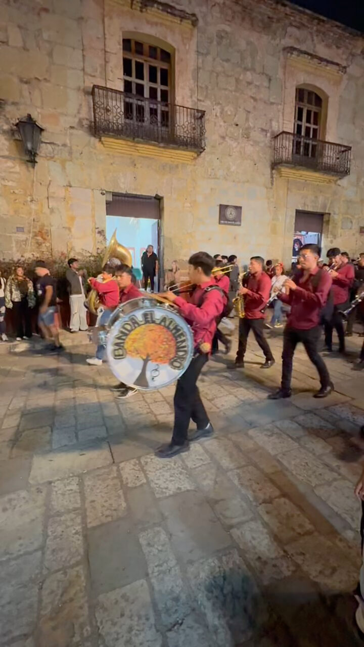 Marching bands play loudly as revelers gather behind them to walk the streets of Oaxaca during Dia de los Muertos celebrations
