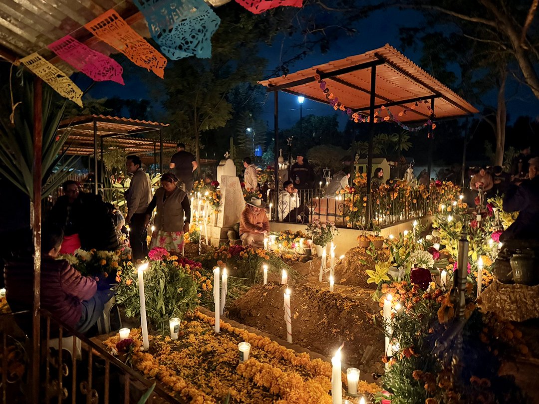 The tradition of Dia de los Muertos brings families to the gravesites of beloved family members to honor them with candles, flowers, and colorful memorabilia